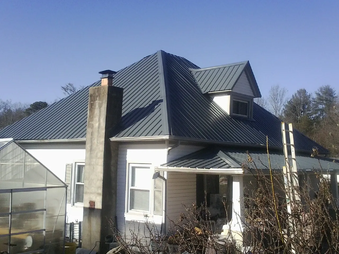 Dark blue standing seam metal roof on a white farmhouse with dormer — Slate & Tile Roof Repair by Roofing Brothers in Thompsons