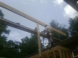 Carpenter setting a ridge beam over a new addition frame — Ice Dam Removal by Roofing Brothers in Thompsons