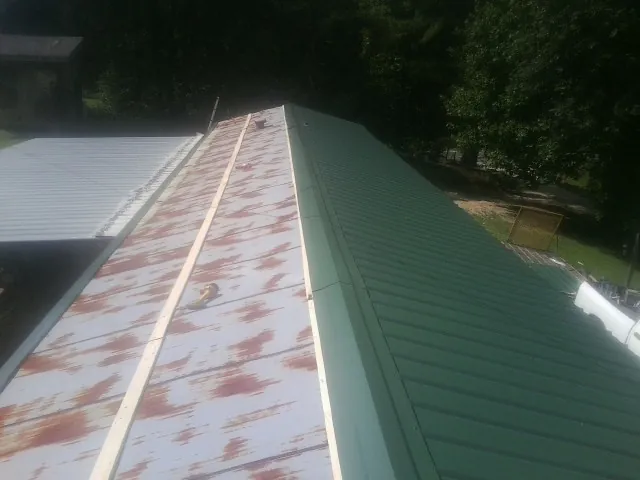 Old rusted panels beside newly installed green metal roofing — Wind Damage Roof Repair by Roofing Brothers in Thompsons