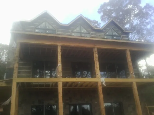 Dormers and porch framing on a large log home under construction — Roof Coating work by our crew in Thompsons