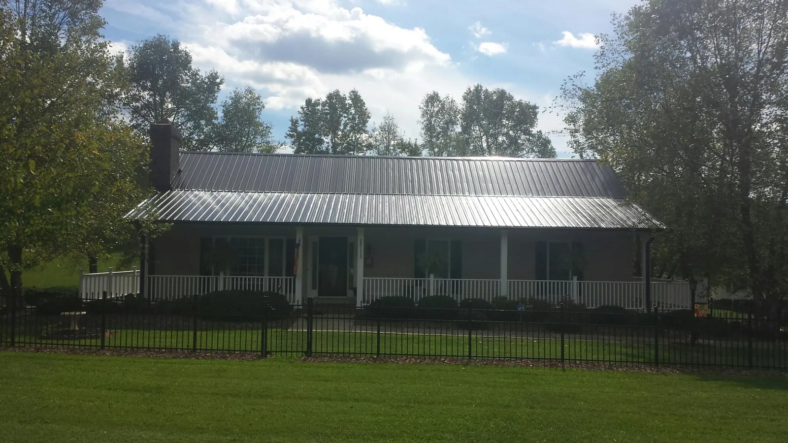 Gray metal roof on a brick ranch with a full width front porch — Gutter Guard Installation work by our crew in Thompsons