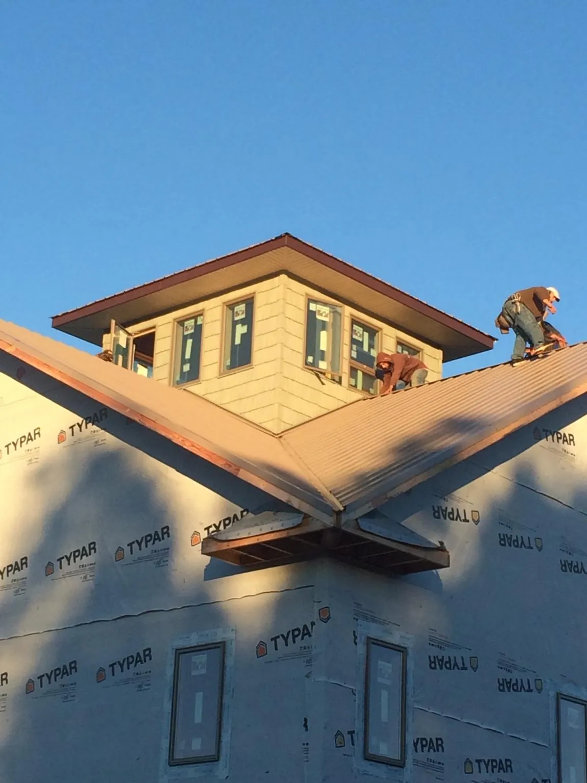 Roofers working around a rooftop cupola on a new metal roof at sunset — Roof Waterproofing in Thompsons by Roofing Brothers
